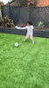 Girl in pyjamas kicking football in garden